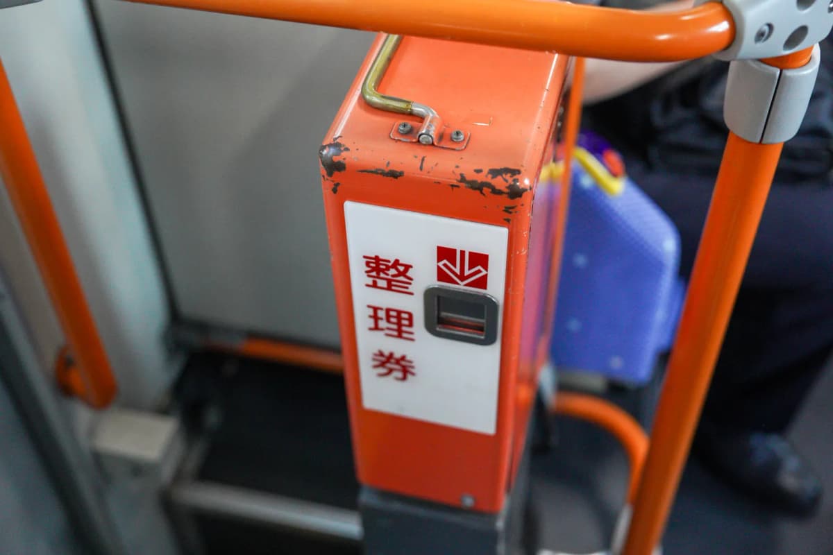 Numbered ticket machine by the rear door of the bus