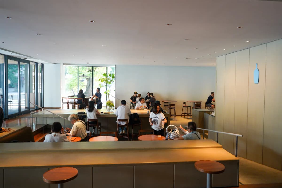 Customers at seats by the glass wall inside Blue Bottle Tenjin