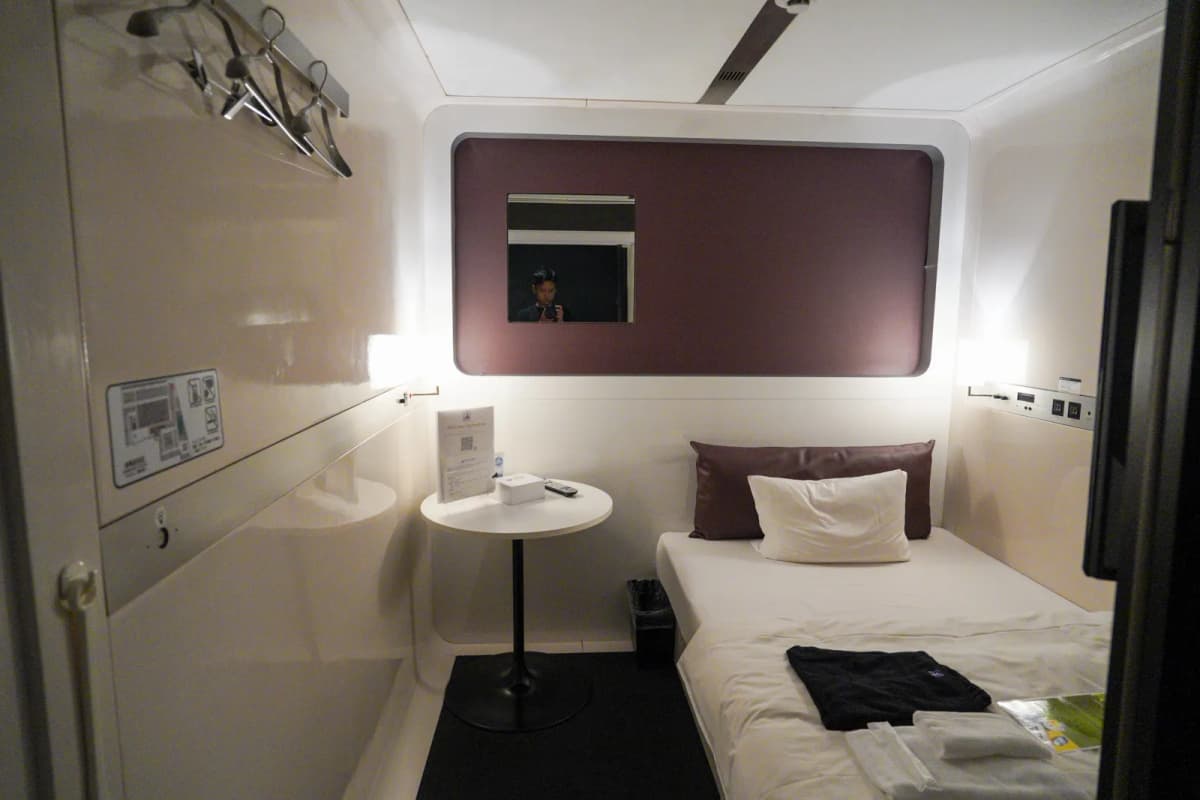 Bed and a small table inside a room at First Cabin Hakata