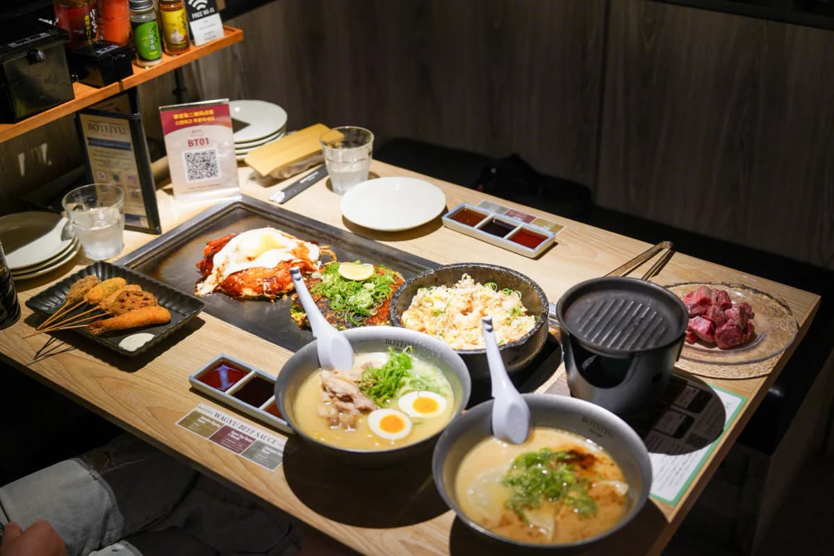 Okonomiyaki, ramen, fried rice, skewers and wagyu on the table at Botejyu Honten Dotonbori