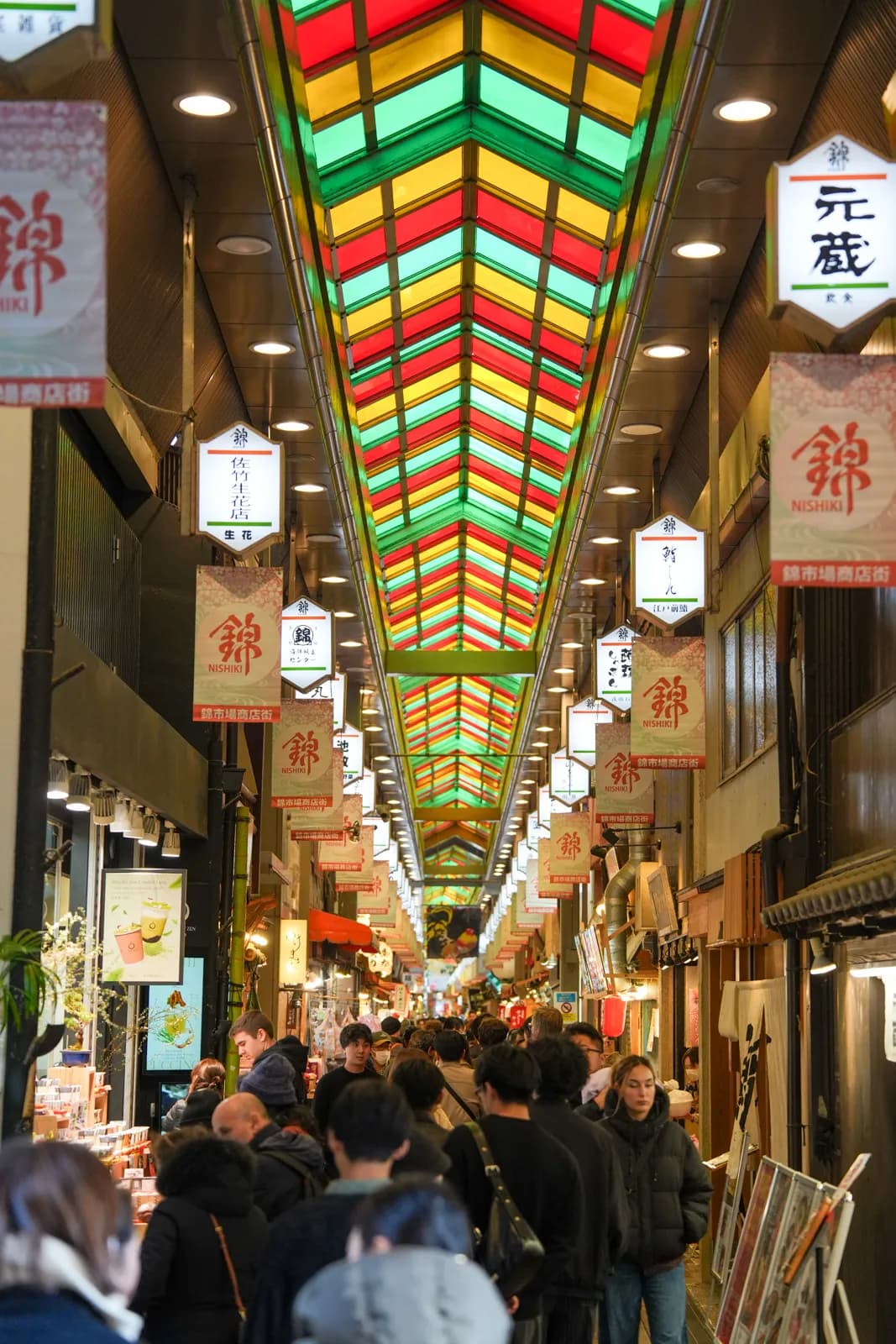 Crowded Nishiki Market arcade under its colorful stained-glass roof