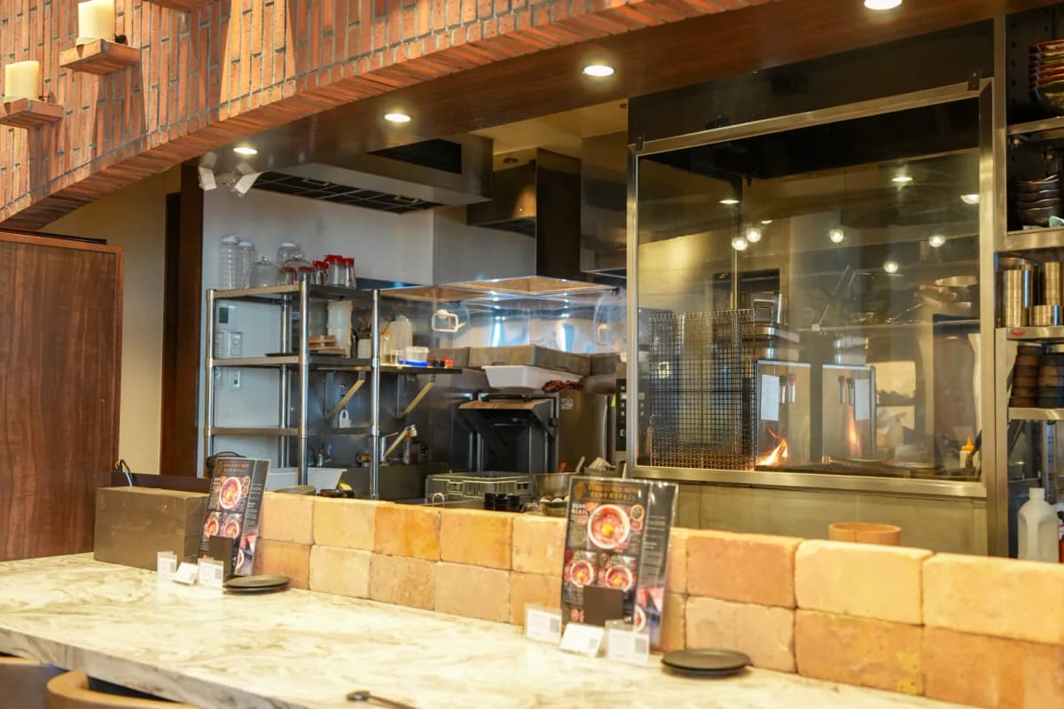 Counter seats facing the open kitchen and wood-fire grill at Keika