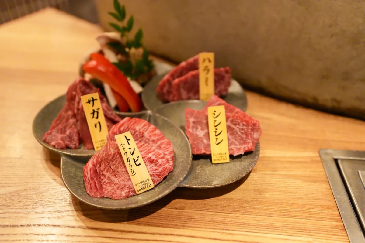 Plates of wagyu cuts labeled sagari, harami, shinshin and tonbi at Yakiniku Akatan