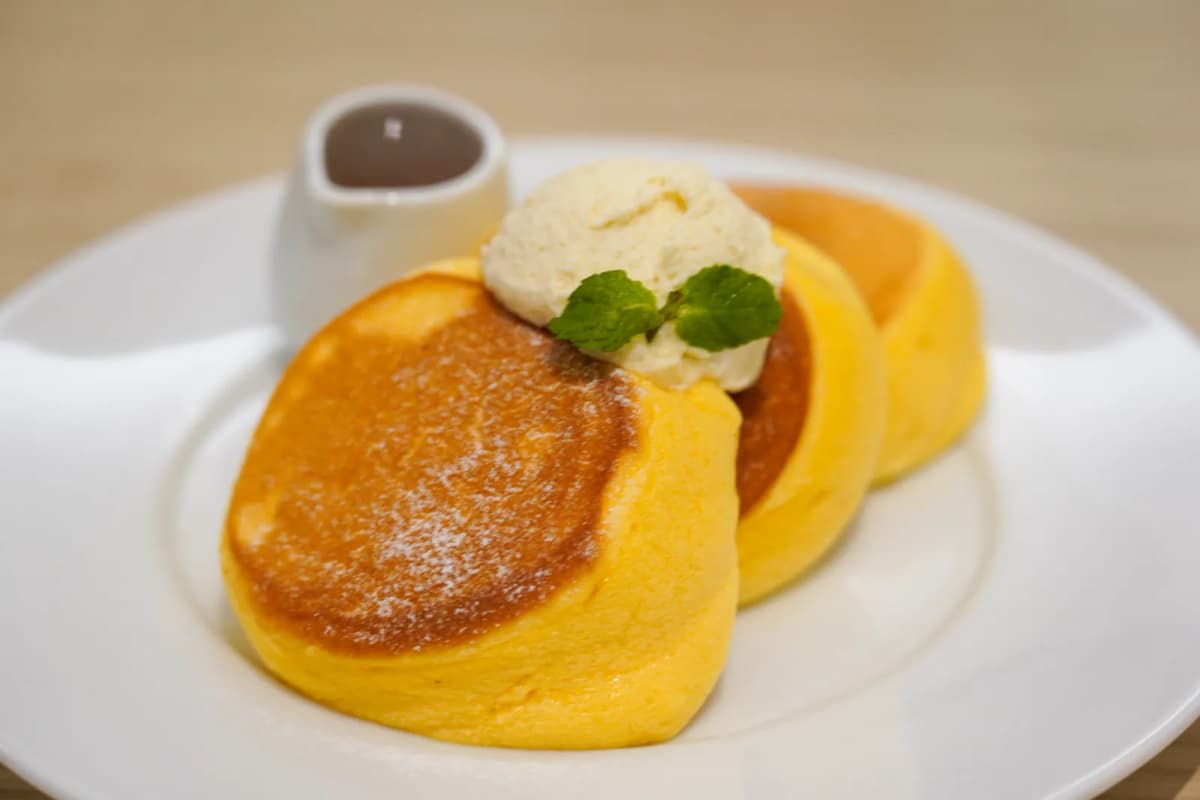 Fluffy pancakes with a scoop of ice cream, mint and a small jug of syrup at Shiawase no Pancake
