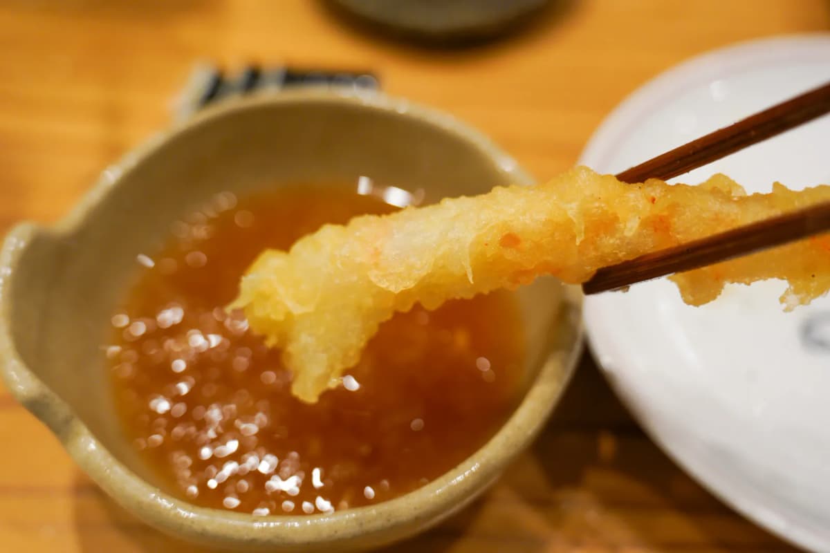 Dipping a piece of tempura into tentsuyu sauce